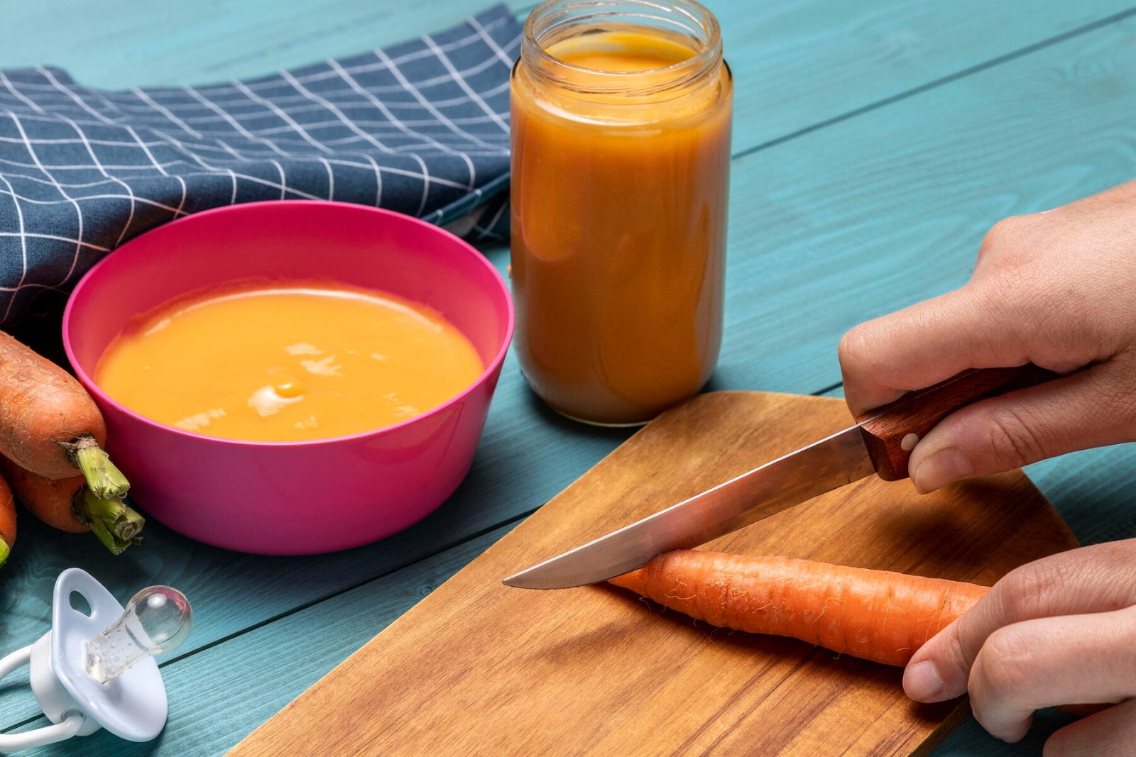 Pureed carrots in a bowl and jar and a carrot being sliced