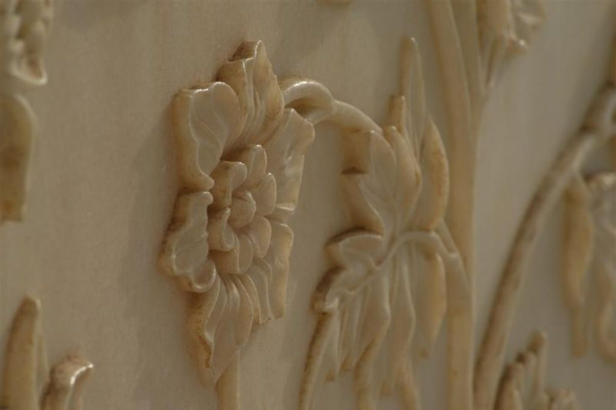 A detailed flower adorns the white marble wall of the Taj Mahal.