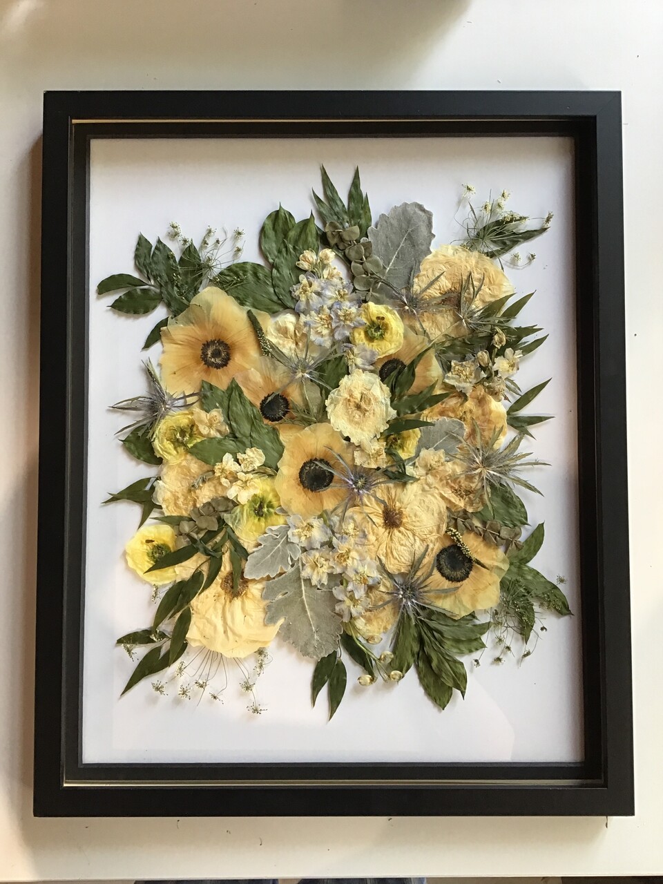 a large black frame with preserved flowers inside