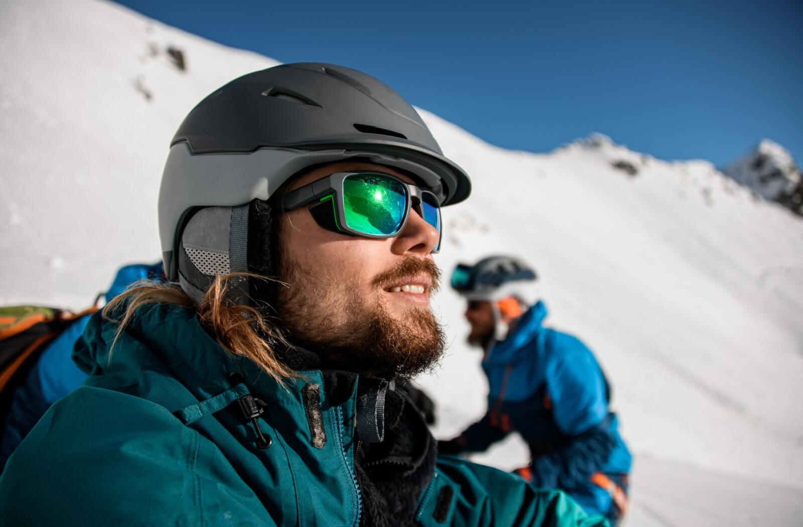 A happy adult enjoys a day on the slopes and protects their eyes from the sun with sunglasses.