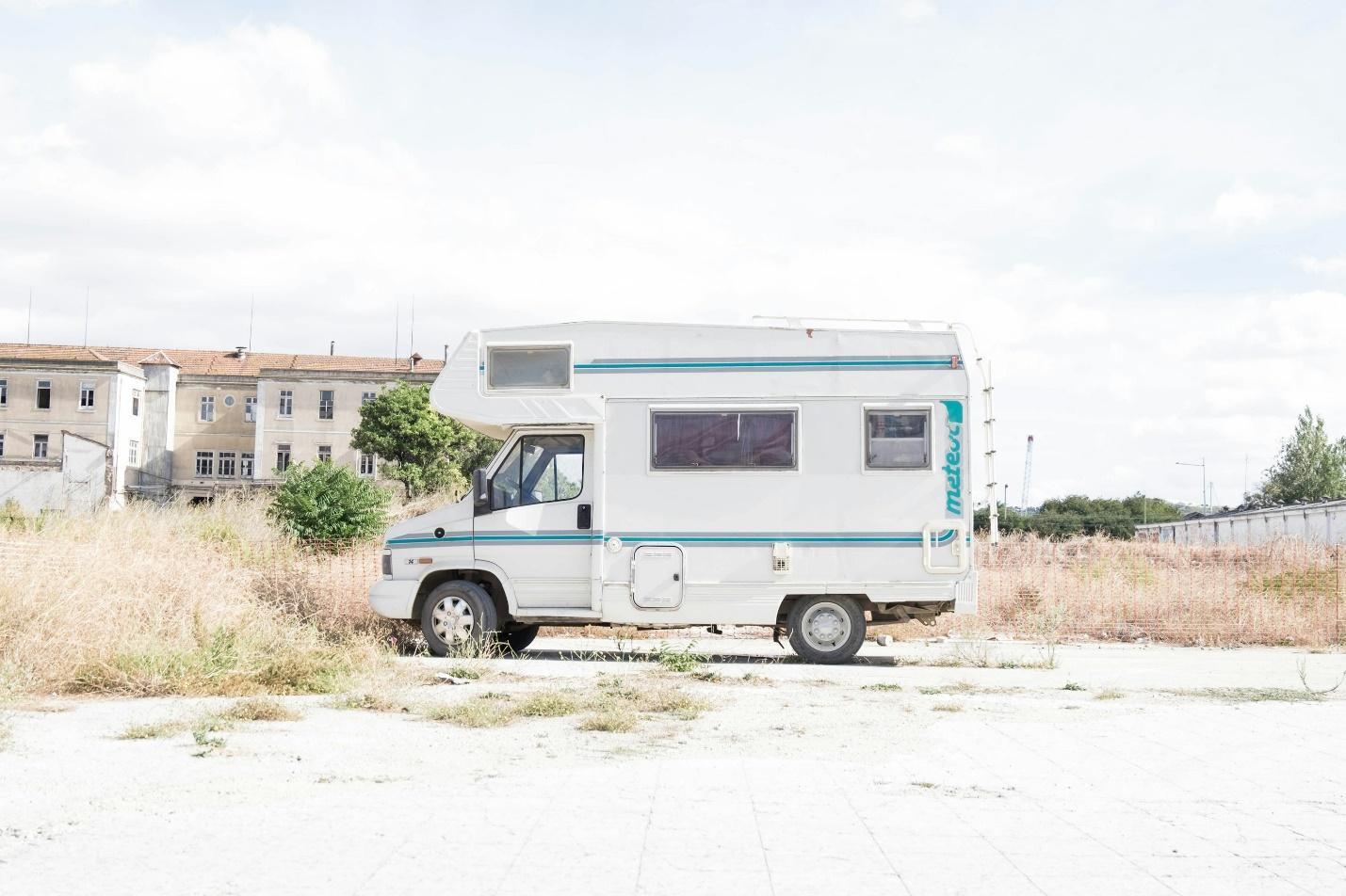 white and blue recreational vehicle parked near grass