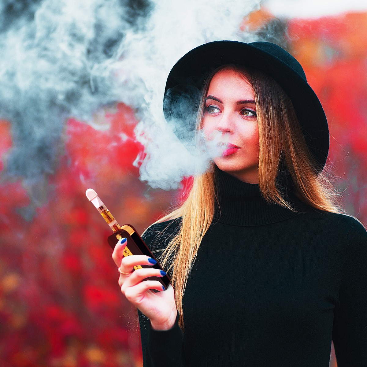 A woman in a black dress wearing a black hat smoking a THCA vape.
