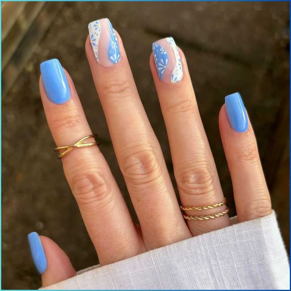 Close up of hands with flowered designed blue nails having White Wavy Pattern Nail Art