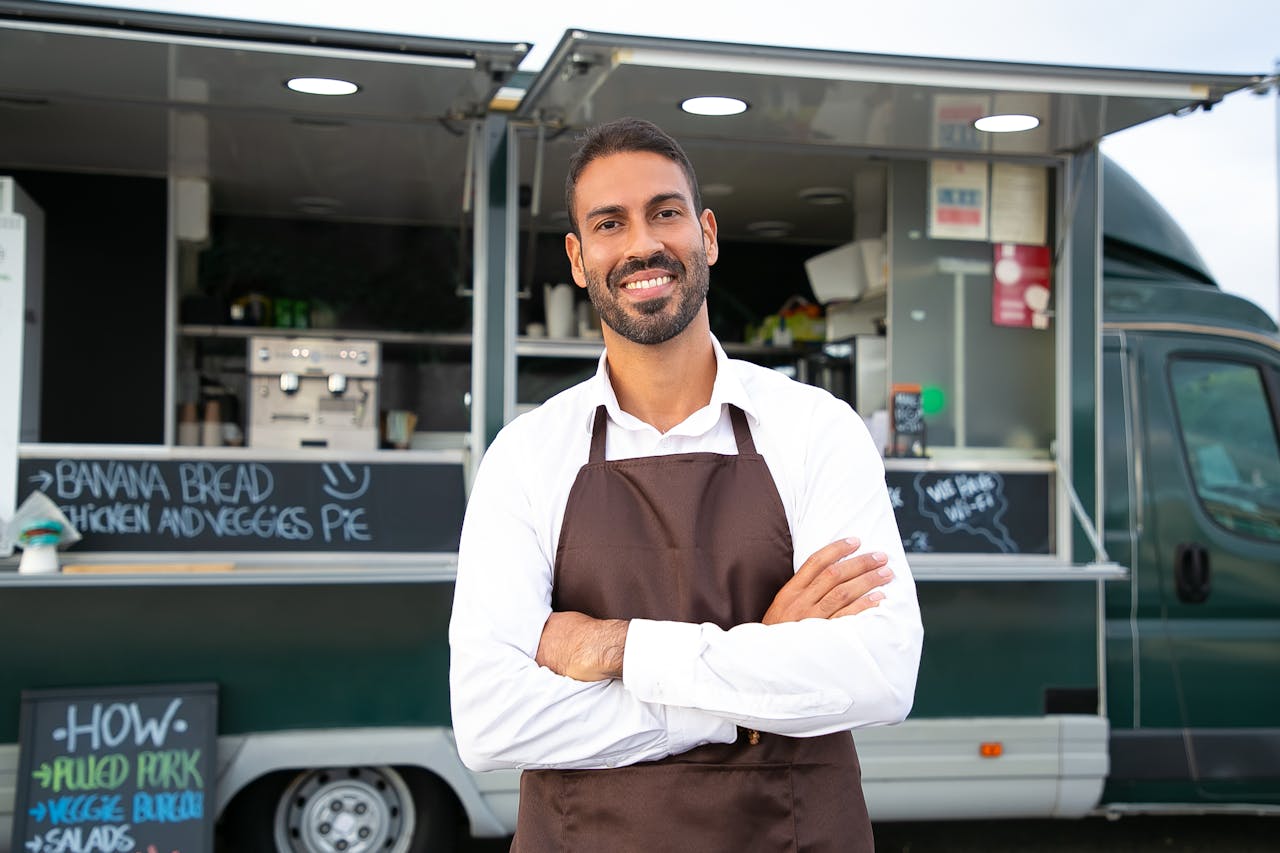 Smiling food truck owner standing confidently in front of his business, demonstrating how to organize your small business for success.