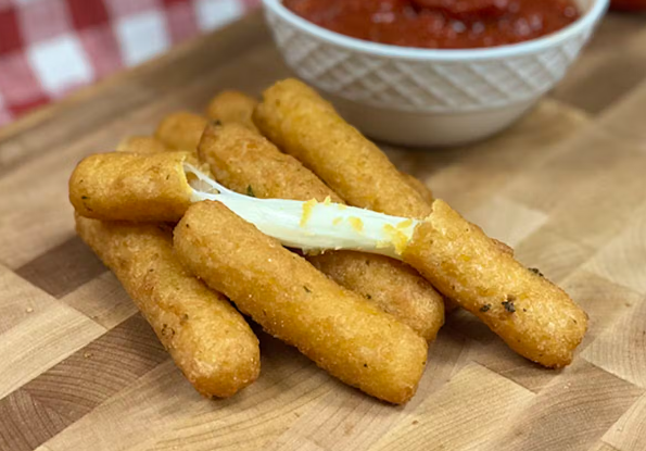 Fried Mozzarella sticks with hot sauce placed on a wooden board, with the mozzarella stick on top broken in two halves with the cheese visible.