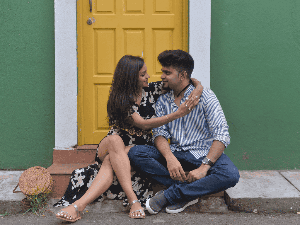 pre-wedding photoshoot of a couple sitting in Fontainhas,smiling and gazing into each other's eyes.