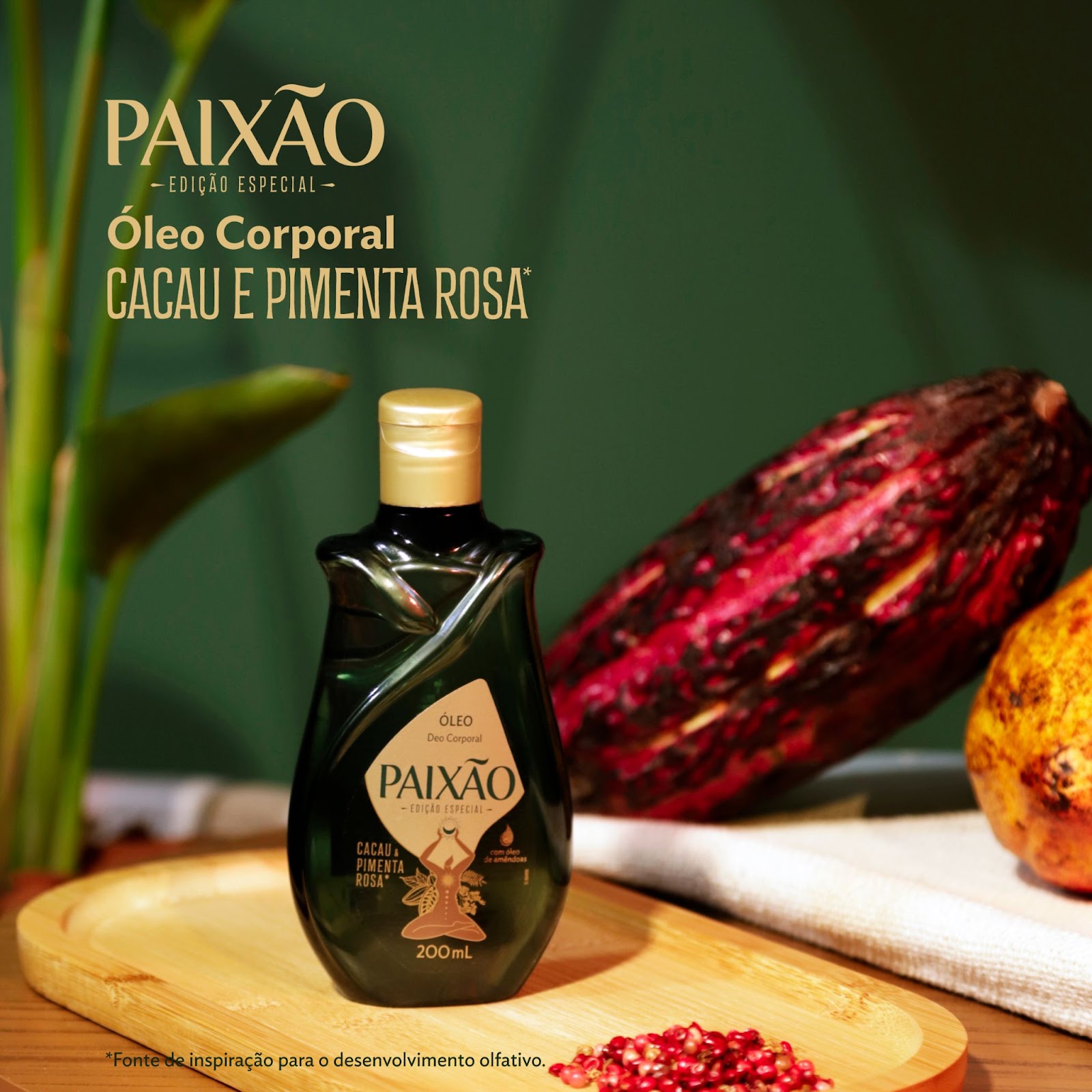 O Óleo Corporal Paixão Feminino Ancestral aparece em cima de uma bandeja de madeira em um cenário decorado com pimenta rosa e cacau.