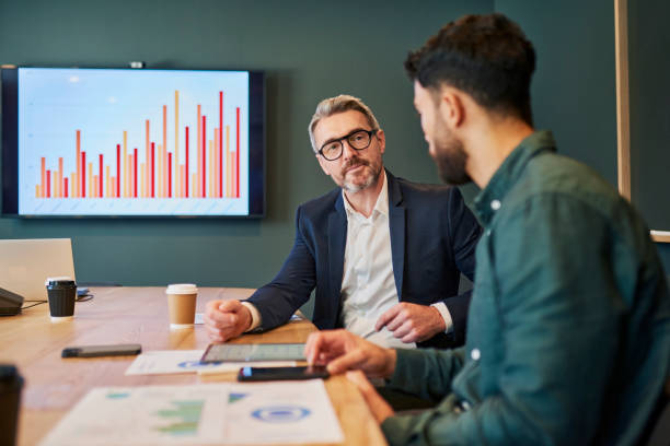 Two men discuss the new plans in a business meeting. 