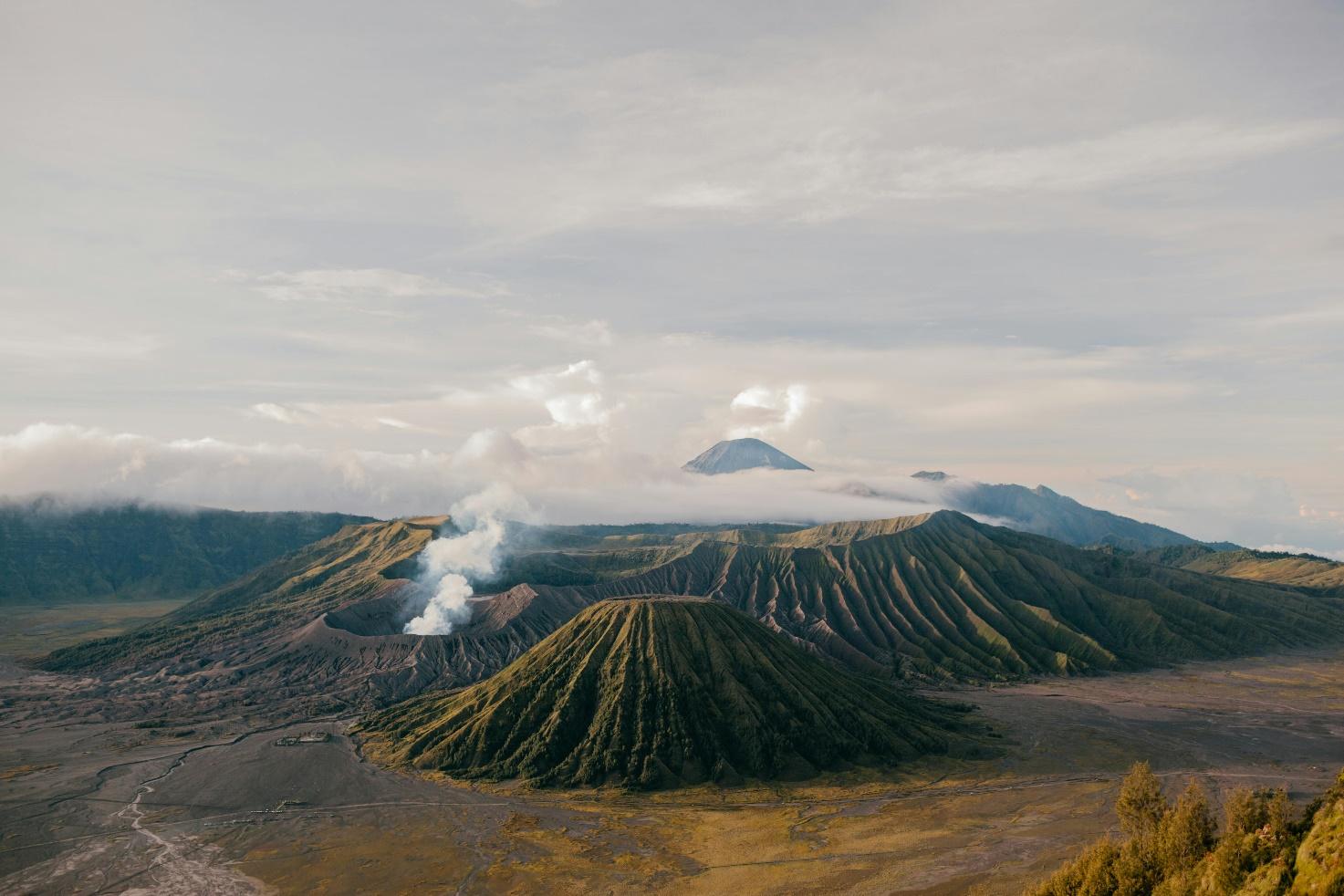 Mount Bromo range with smoke coming out of the groundAI-generated content may be incorrect.