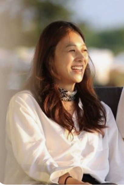 This is a picture of Jang Shin Young wearing a white shirt and smiling