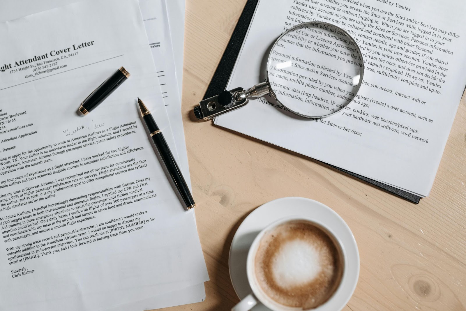 Front view of a cover letter with a pen, magnifying glass, and a cup of coffee