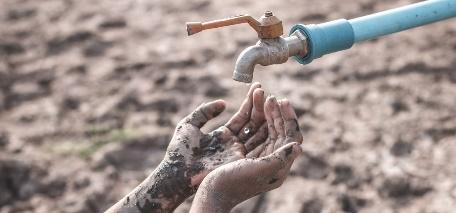 A dirty hands pouring water from a faucet

Description automatically generated