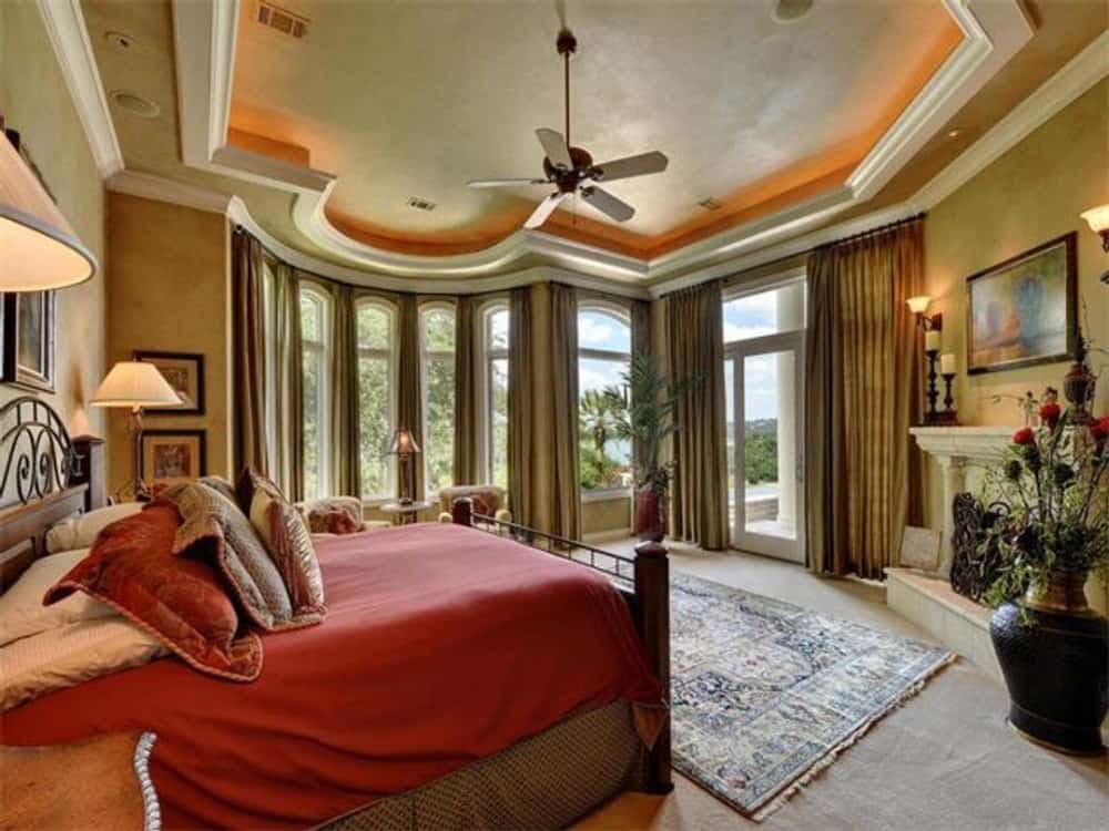 The primary bedroom features a tray ceiling, its own fireplace, and a sitting area by the bay window.