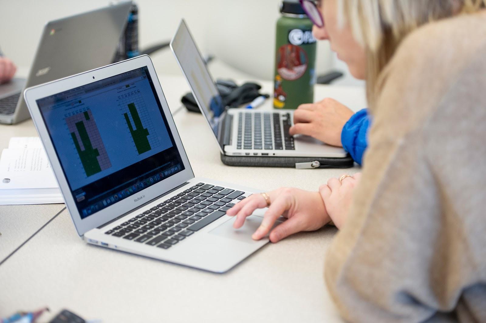 A student leaning over an open laptop, focusing on their work, representing the technical communication learning experience in the Boise State Department of Writing Studies Certificate in Technical Communication.