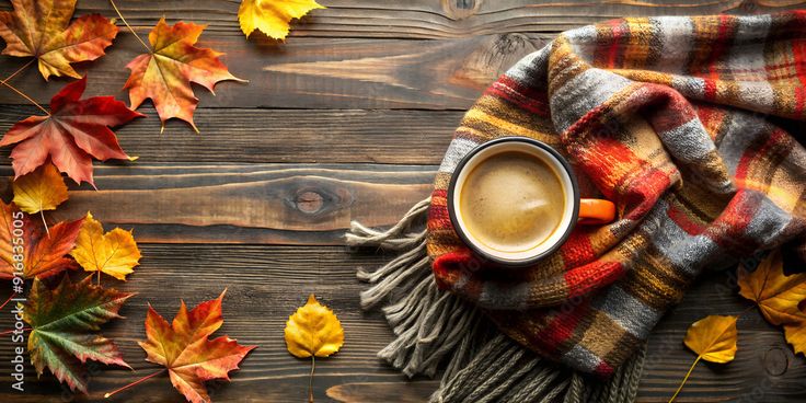 a cup of hot coffee set on the table amongst autumn leaves