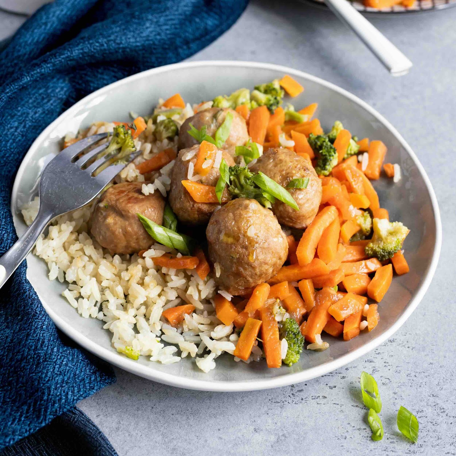 Boulettes de viande de veau servies avec du riz et des légumes sautés.