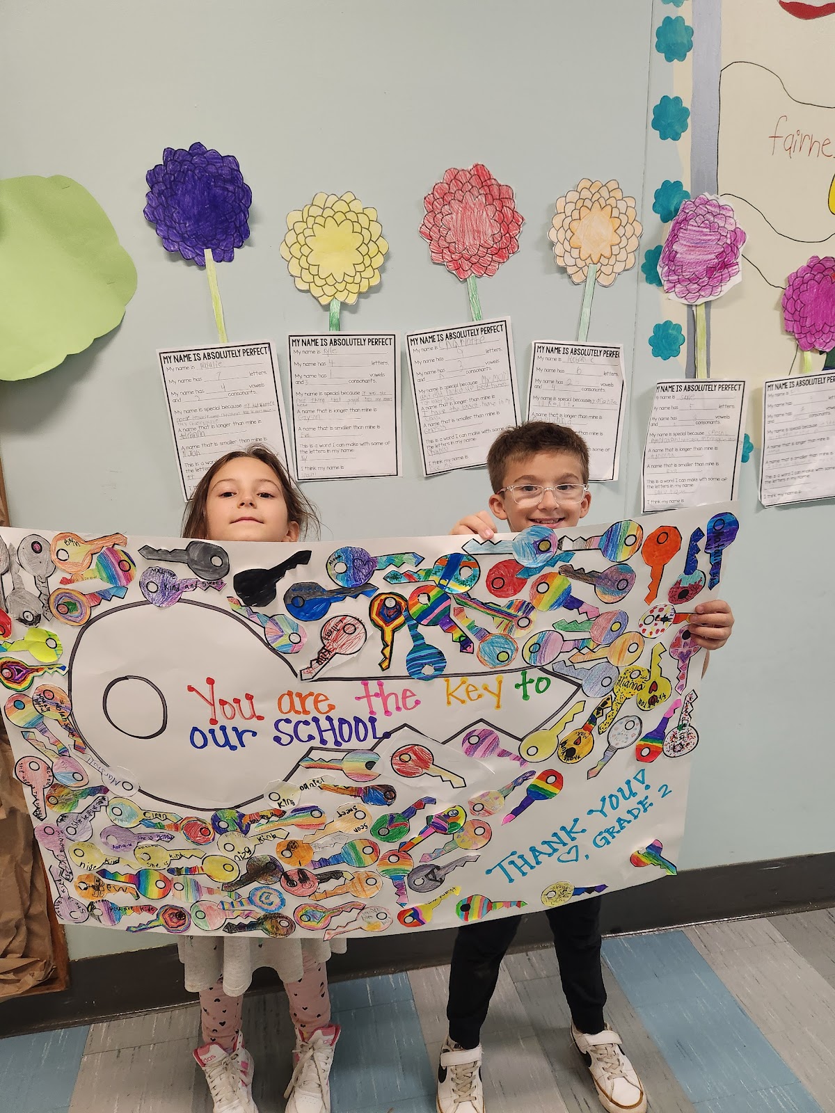 image of 2 students holding up a banner for Custodian Appreciation Day.