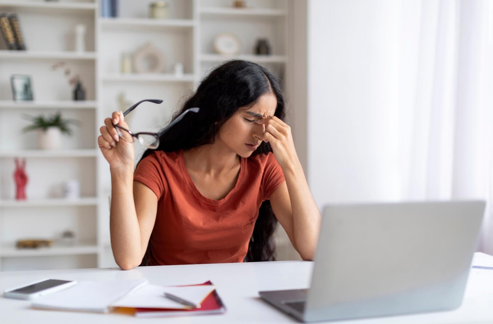 Woman experiencing eye strain while working on a laptop.