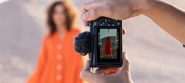 Usage image of hands holding the camera vertically and shooting a female model, who is visible on the camera screen