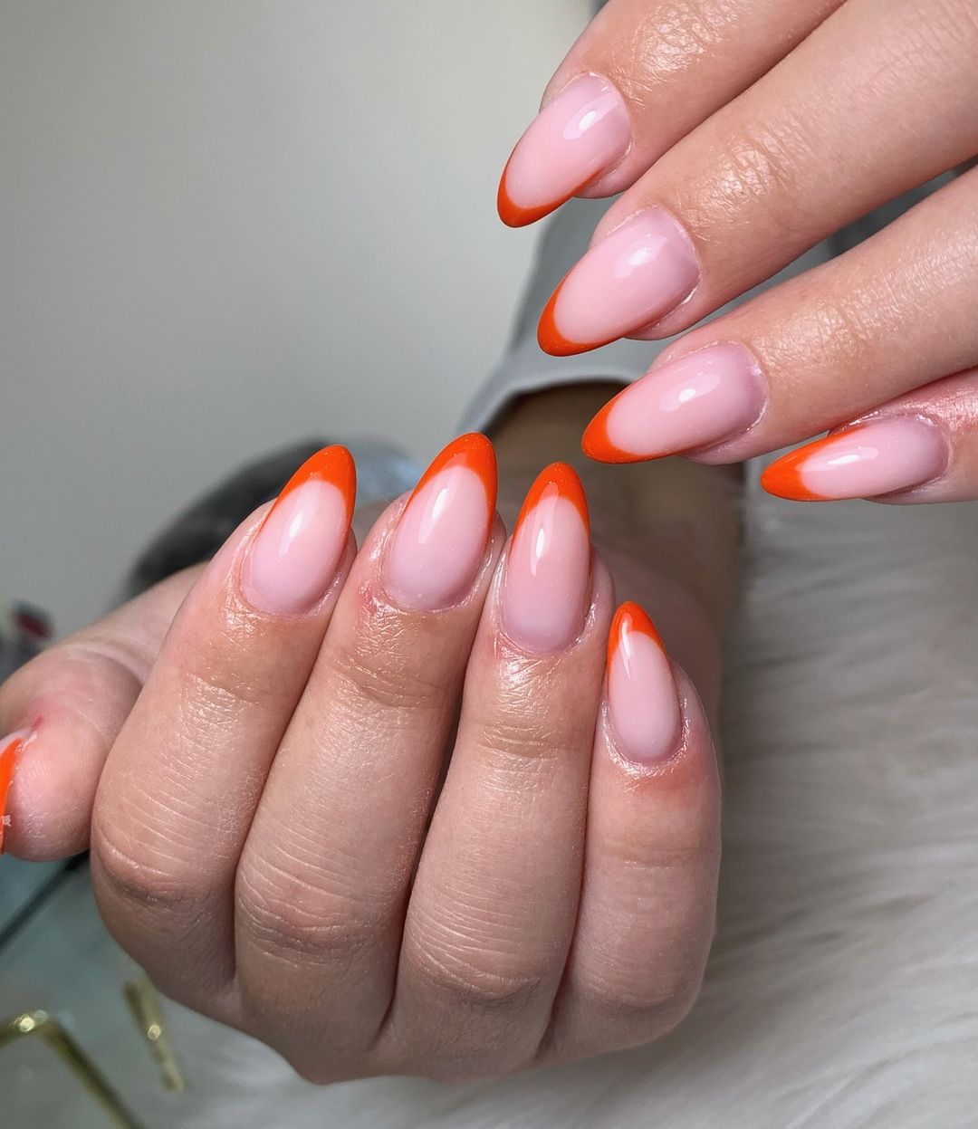 Close up of nails with glittery orange nails having Classic Orange French Tips