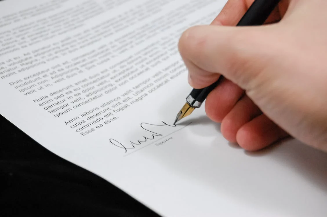 Close-up of a hand signing a document with a fountain pen, representing the finalization of an agreement or contract.