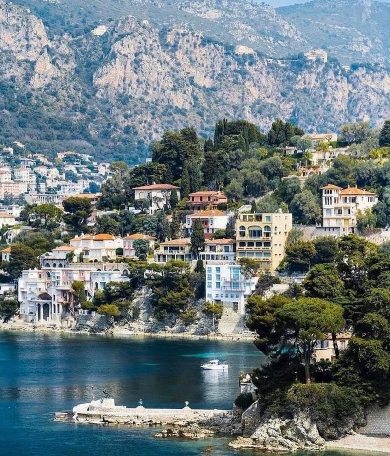 A body of water with buildings and mountains in the background

Description automatically generated