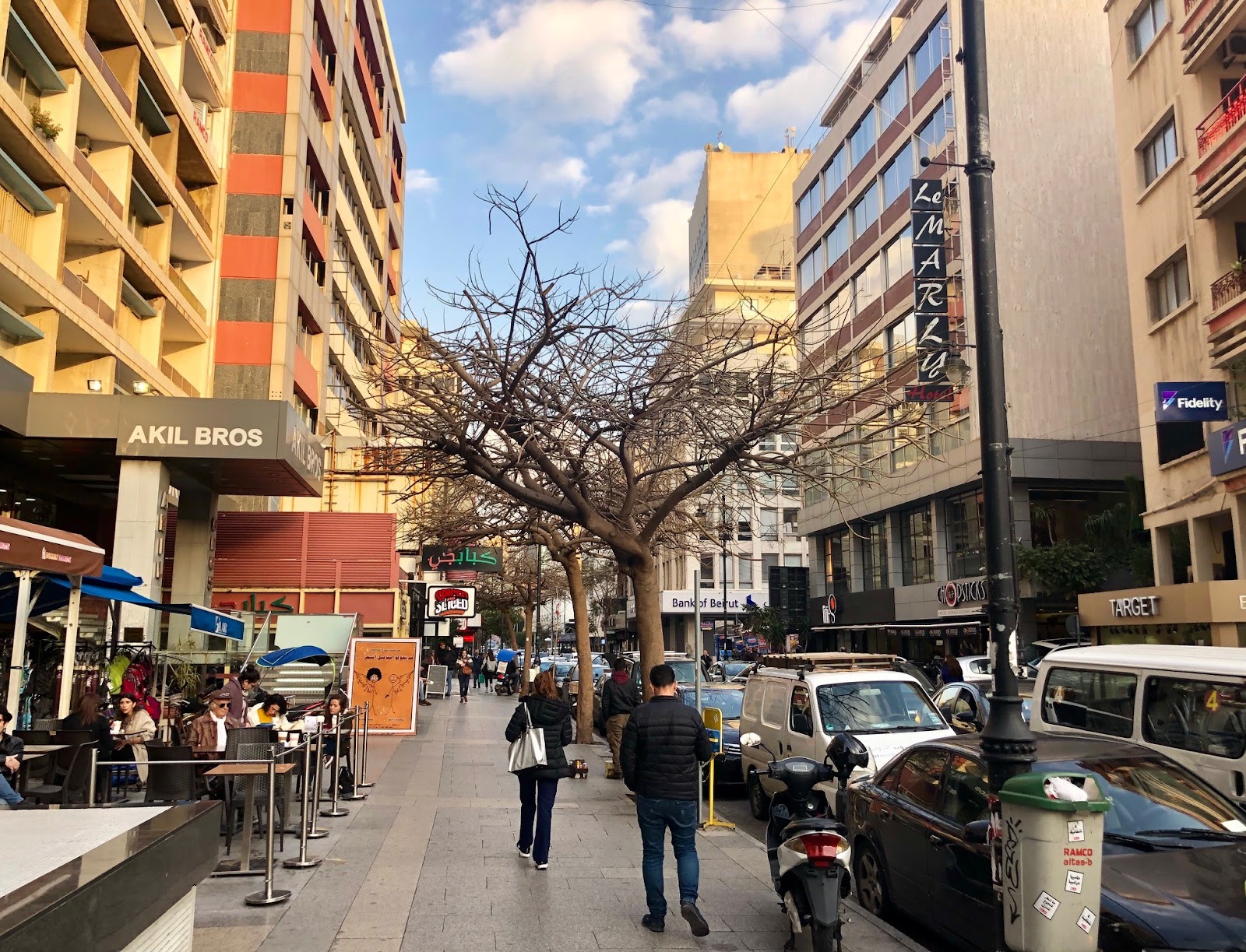 شارع الحمرا المزدحم في بيروت، لبنان، مع محلات ومقاهي ومباني حديثة، والناس يمشون على الرصيف، يلتقط جو المدينة الحضري النابض بالحياة