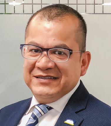 Hombre sonriendo con lentes y traje

Descripción generada automáticamente