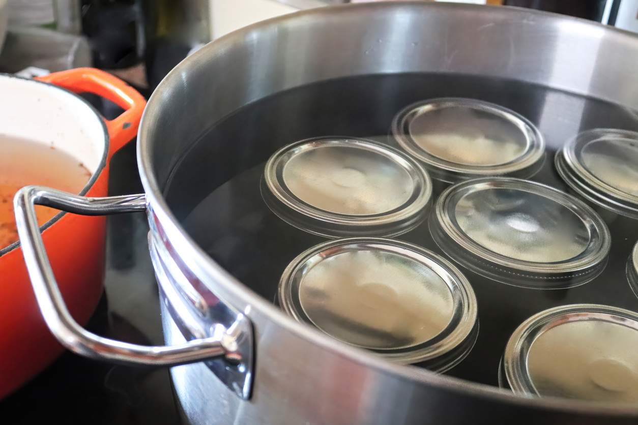 Several pickling jars in a large pot full of water.