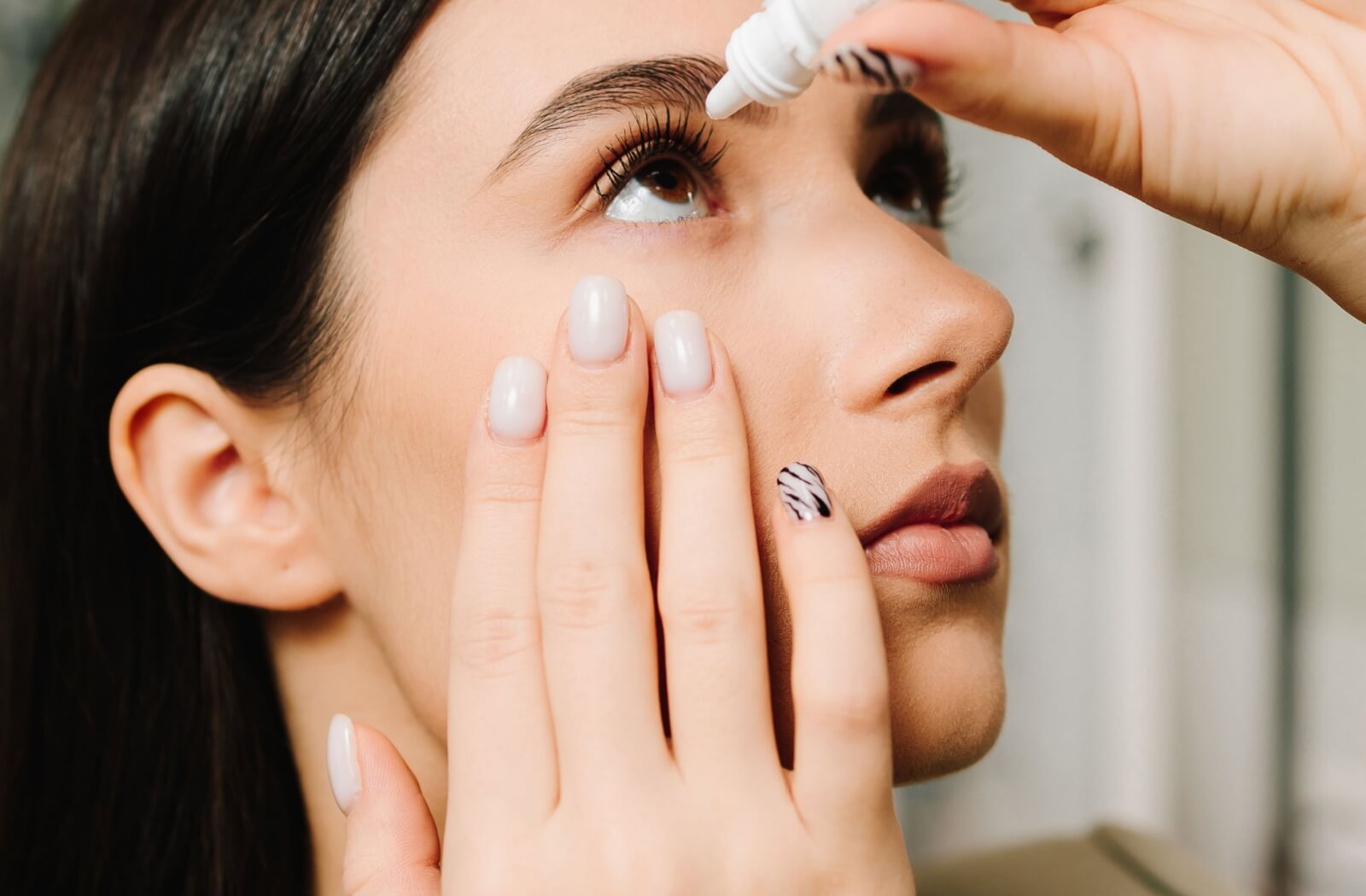 Close-up of a person applying eye drops for relief from dry eye symptoms related to allergies.