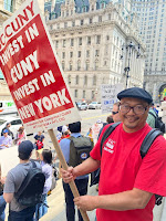 Frans in a union t-shirt at a rally holding a sign, "Invest in CUNY, Invest in NY"