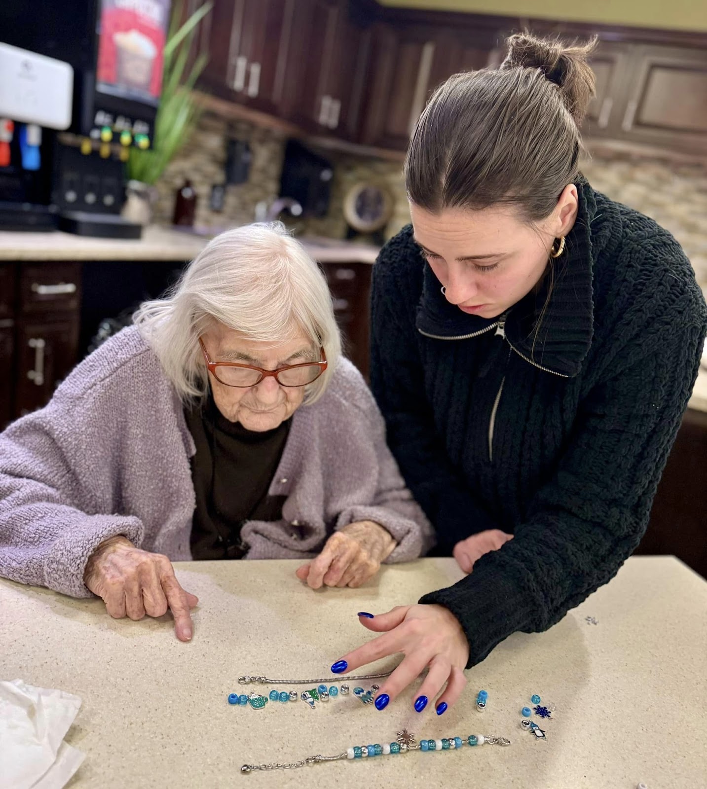 A Village Walk senior care team specialist sorting beads and necklaces with a senior citizen at a table