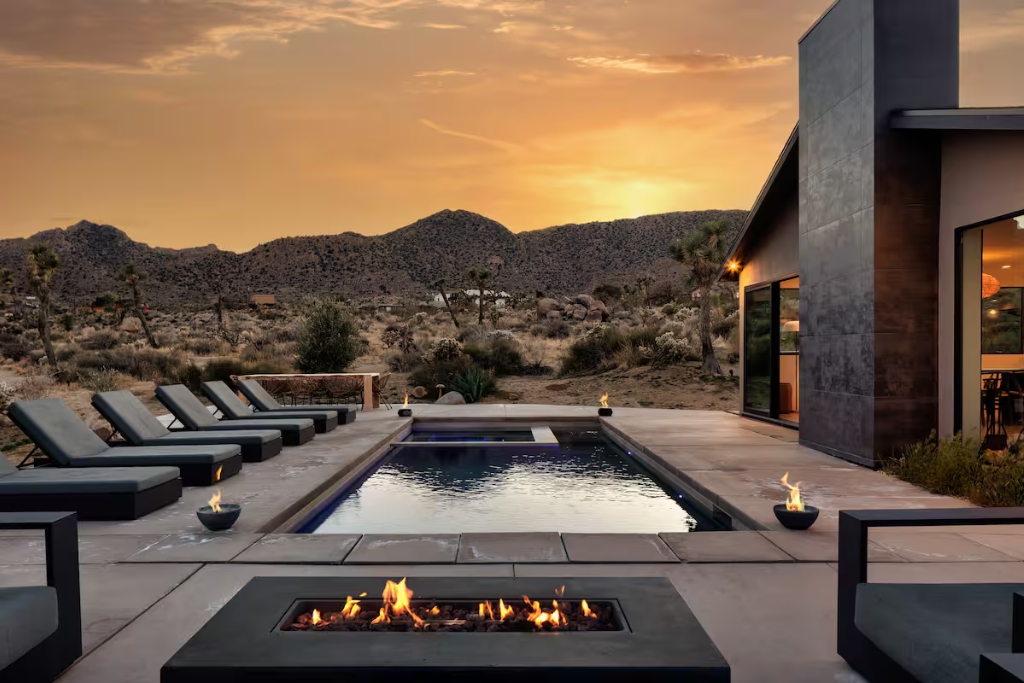 airbnb in joshua tree california with a pool fireplace loung chairs and panoramic desert views during sunset