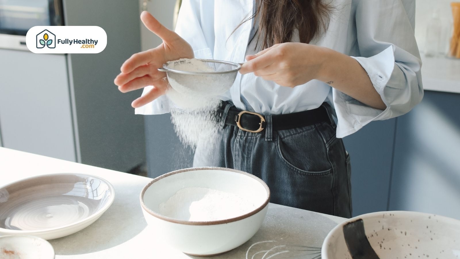 Woman sifting flour gently into a large mixing bowl
