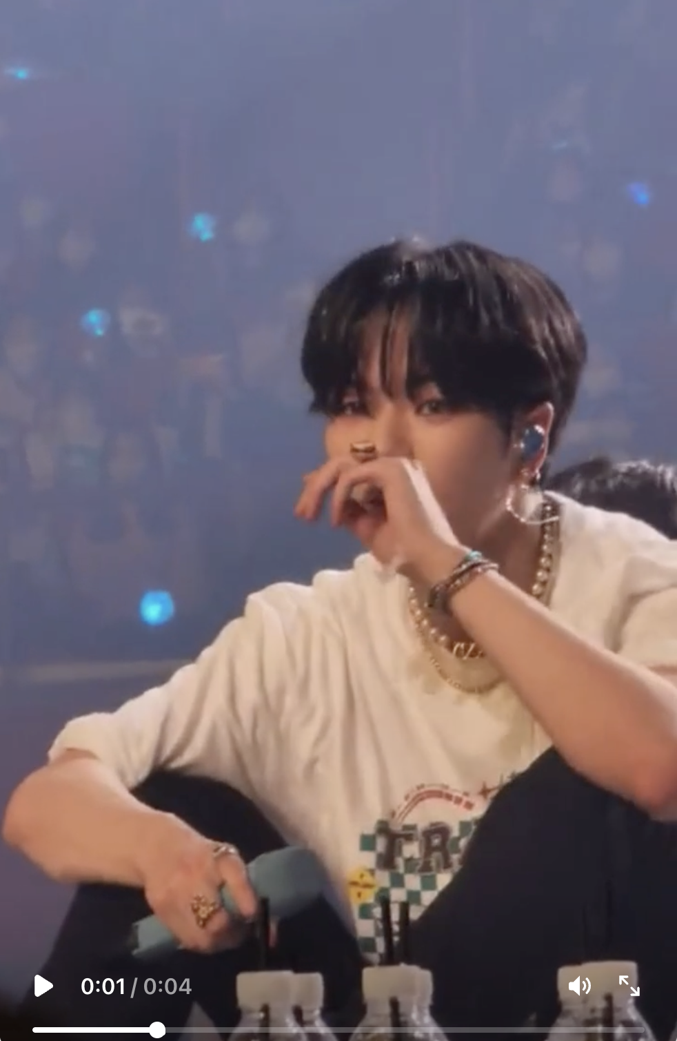 This contains an image of TREASURE Jaehyuk on stage exhaustion video with his hand on his mouth 