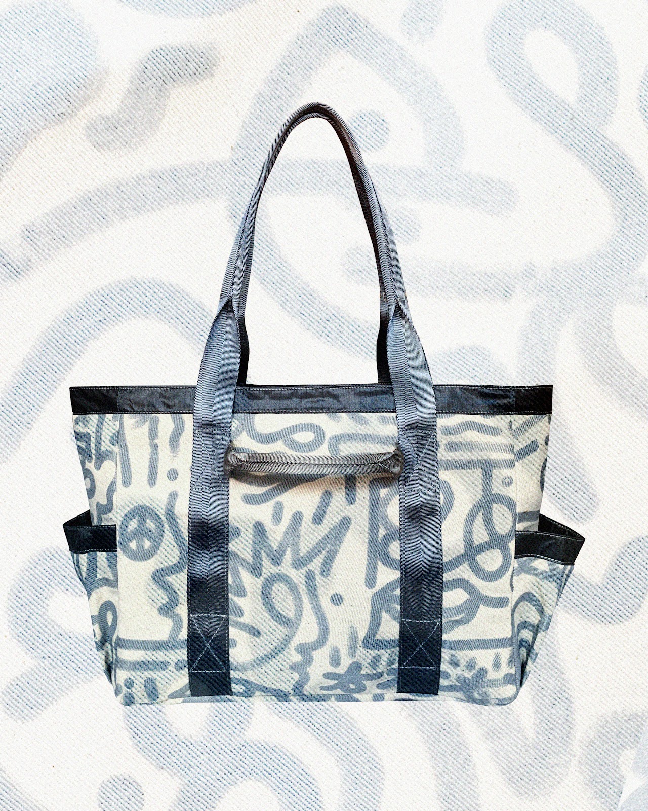 A full shot of the Utility Tote with abstract blue design over white canvas. 