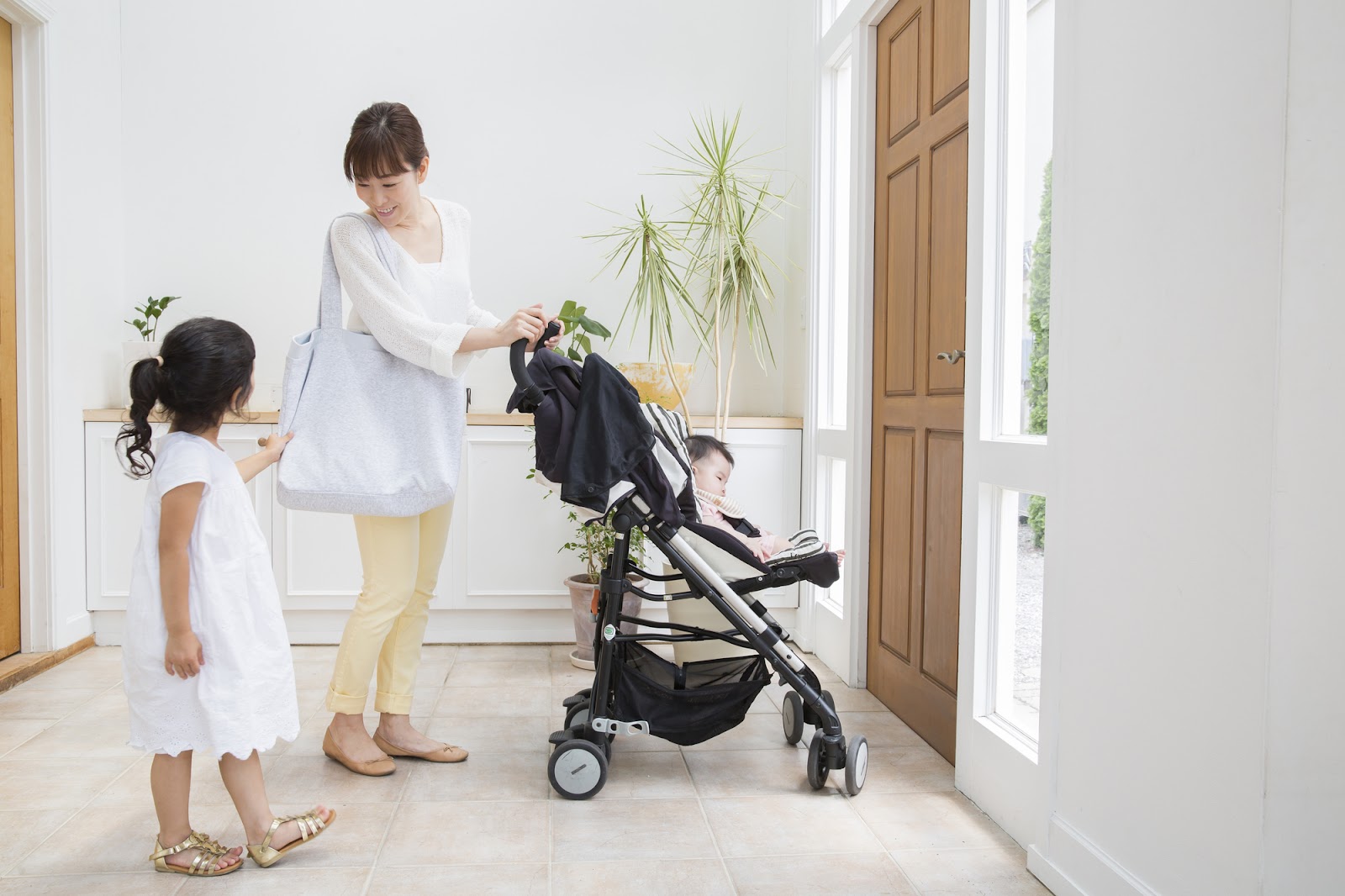 玄関でベビーカーに乗る赤ちゃんとお母さんと女の子