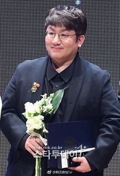 This contain: a picture of  Bang Si Hyuk's in a suit and tie holding a bouquet of flowers while standing next to another man