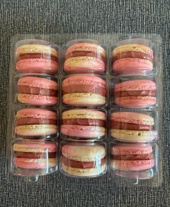 A plastic case of yellow and pink macarons.