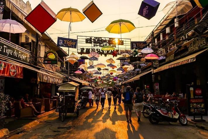 A group of people walking down a street with umbrellasDescription automatically generated