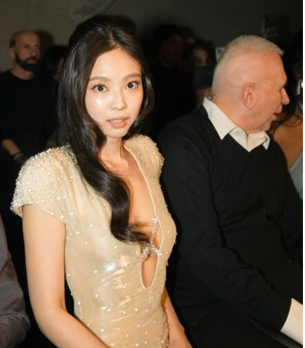 This contains an image of Jennie seated next to Jean Paul Gaultier himself