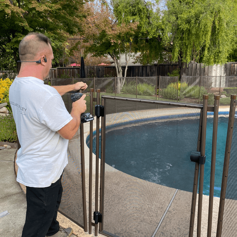 Lifeguard on Duty pool fence installer is finishing a pool fence installation in a California backyard