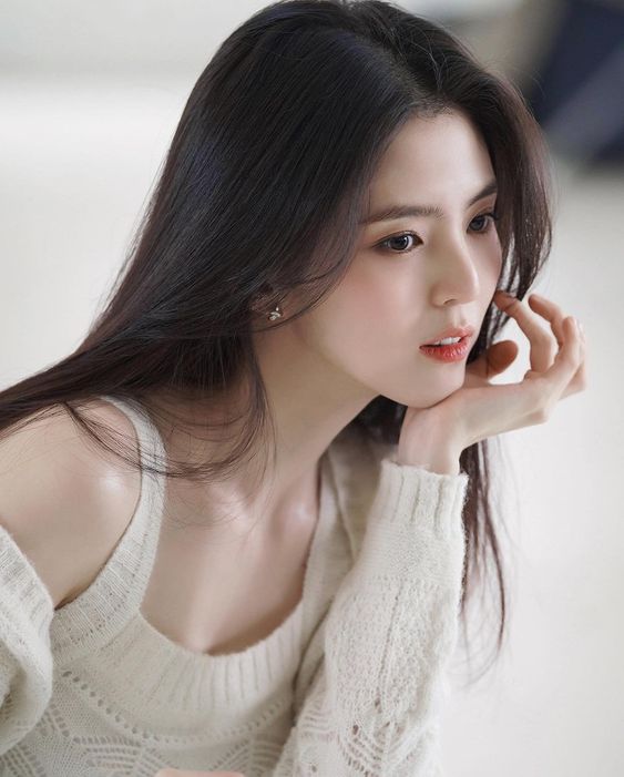 Picture of Han So Hee wearing a off-white sweater with her hand on her jaw