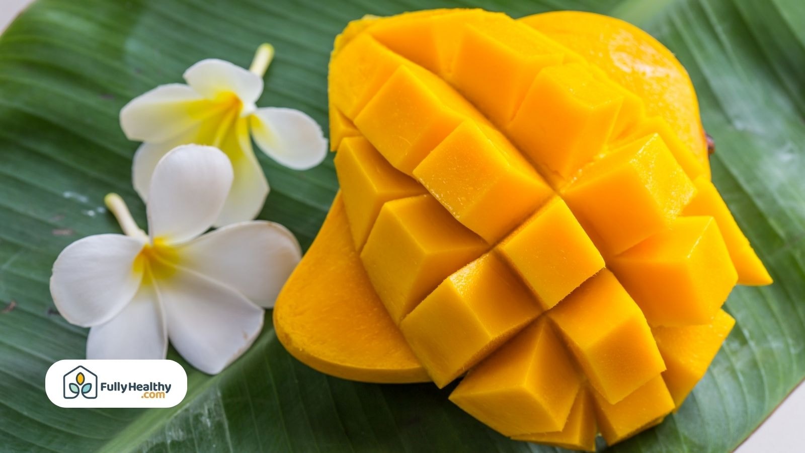 Cubed mango with white flowers on green banana leaf