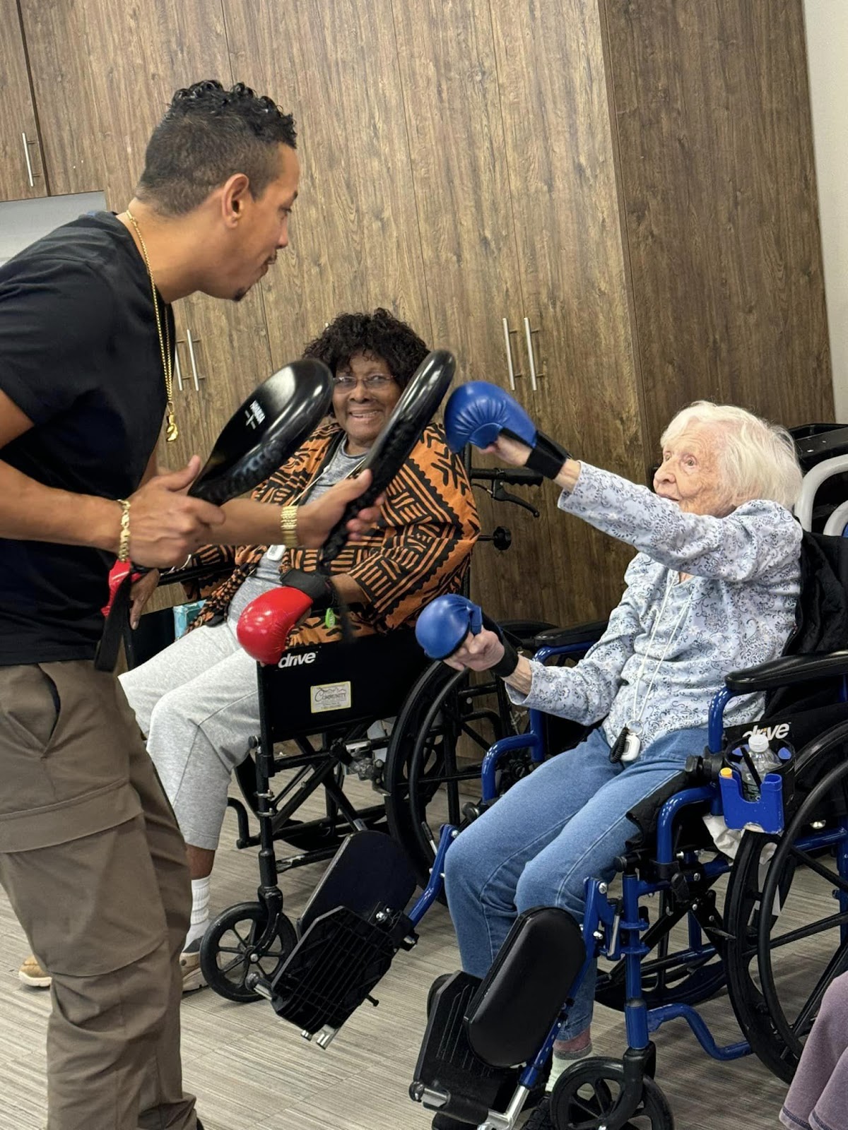 A recreation staff and senior citizen engaged in a shadow boxing class