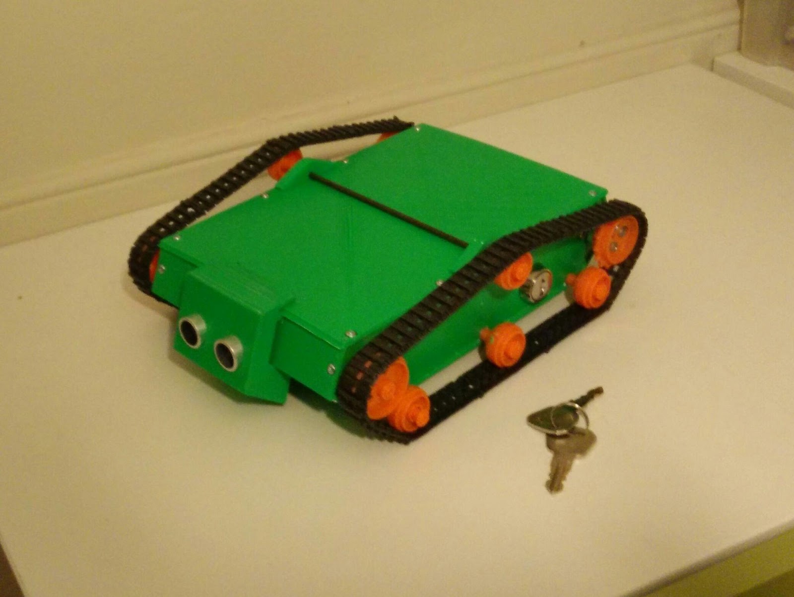 A green toy with orange wheels and a key

Description automatically generated