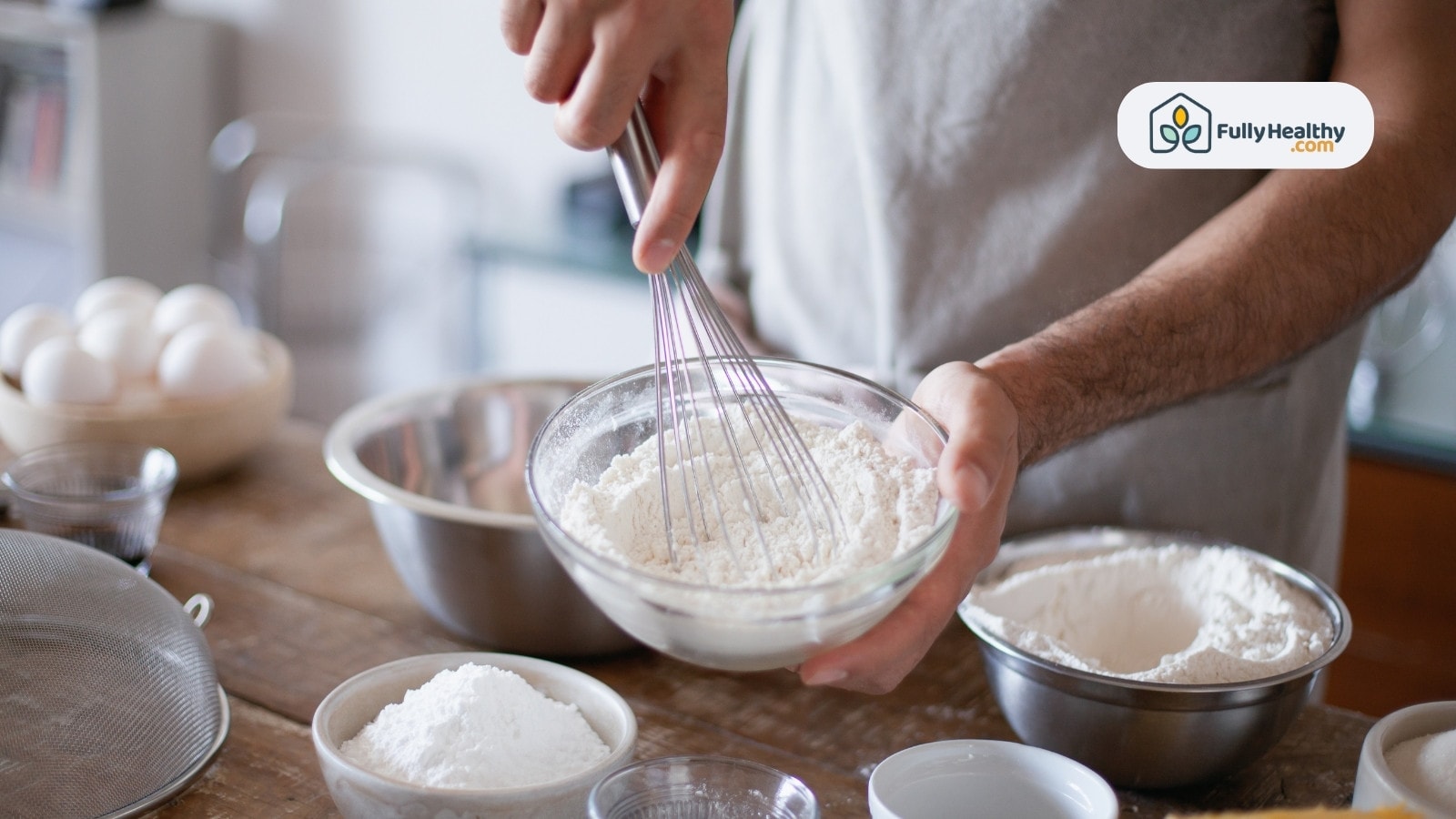 Man whisking flour mixture in glass bowl for baking preparation