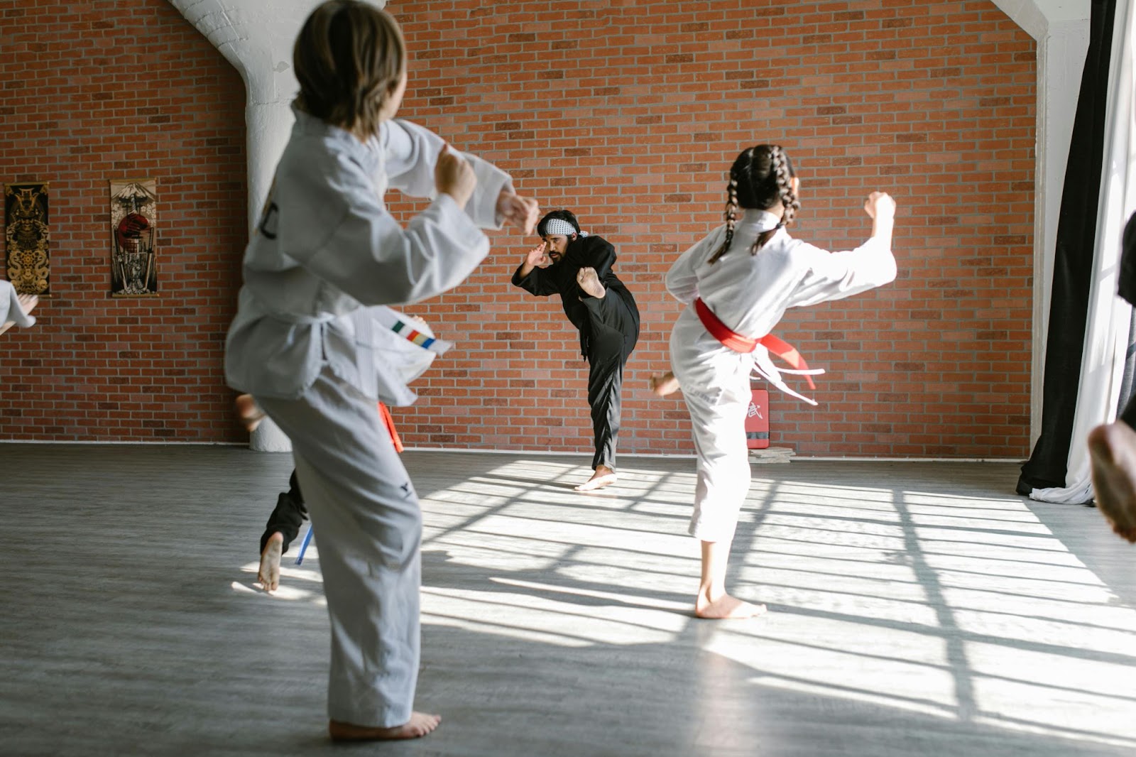 A martial arts instructor and three young students practice kicking techniques in a training session. 