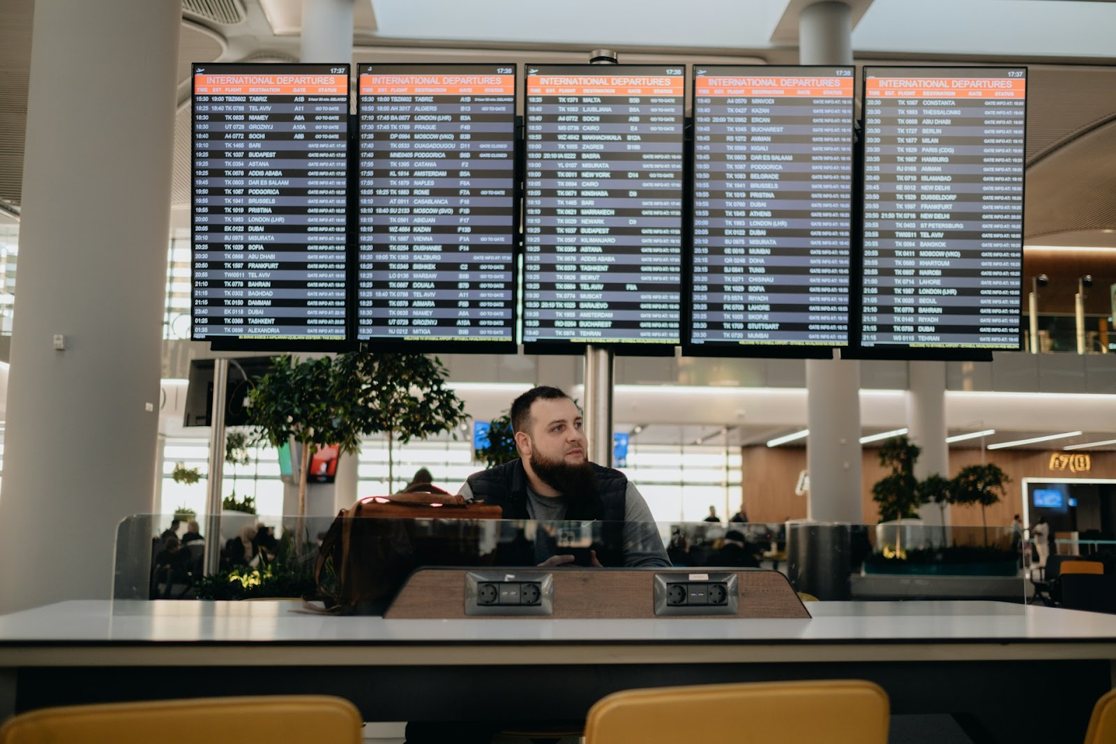 A man sits at a counter at an airport, looking off into the distance