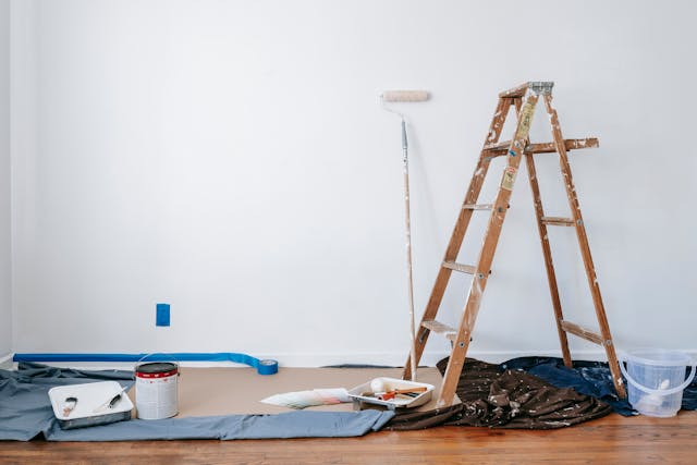 ladder and paint roller sitting against a wall